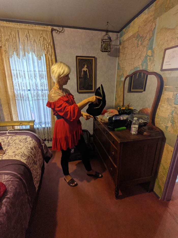 My wife reviewing her pirate costume in front of the antique bureau and mirror in our room. Also note the wall behind bureau with old maps for wall paper