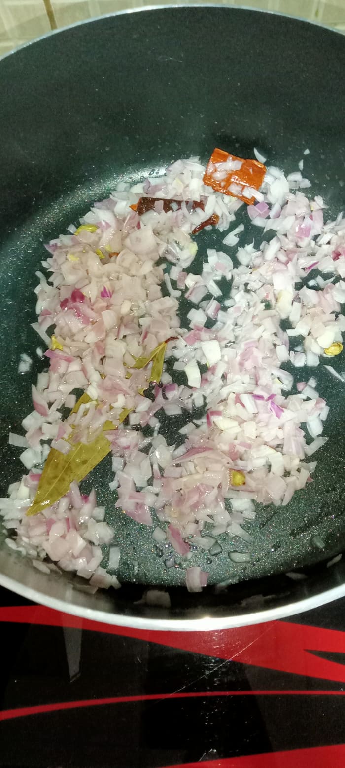 Heat some ghee and oil in a cooking pot. Add bay leaves, green cardamom, cloves, and cinnamon. Sauté until fragrant. Add chopped onion. Cook until translucent.