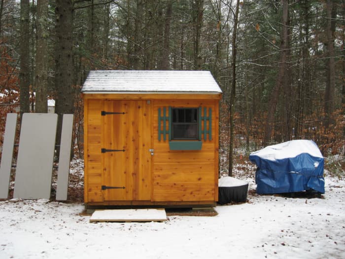 The snow slides right off the picnic table when it is stored like this. On the right is the fire pit with its cover and a deck box with a tarp over it.