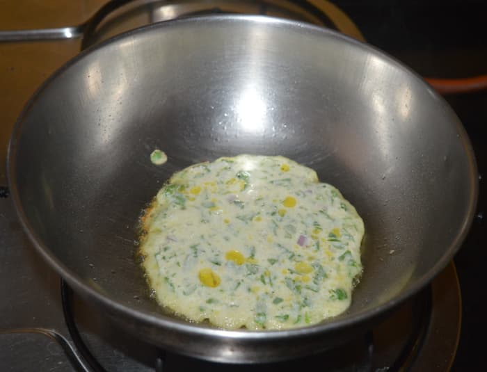 Step four: For making dosas, heat a pan and grease it with some oil or ghee. Add 1 1/2 ladle full of batter and slightly spread it. Add a few drops of ghee or oil to the top. Keep the pan at medium-low heat and cover the pan.
