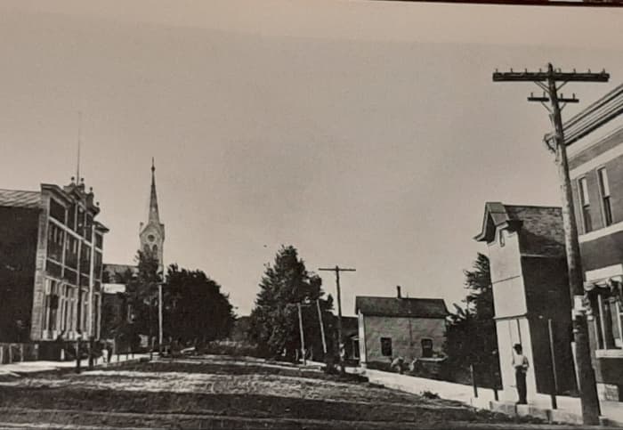 Spire of Saint Thomas Aquinas Church seen on left looking from Main Street down River Road. Picture taken in early 1900s.