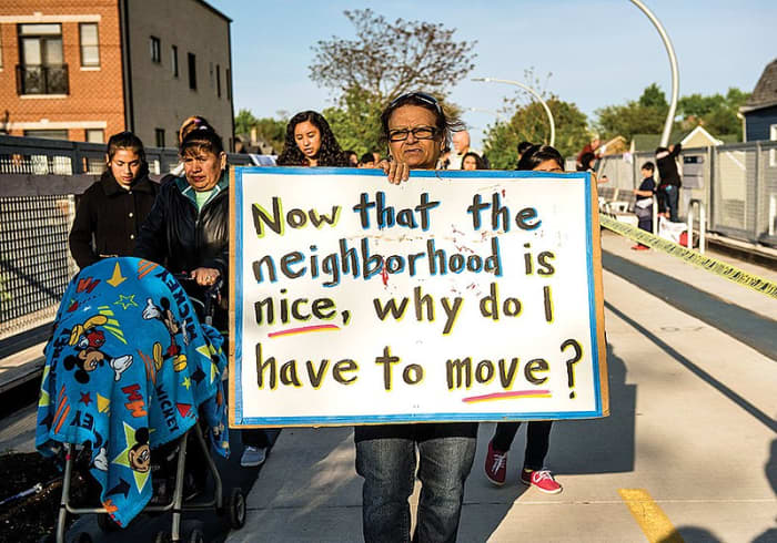 People take to the streets to protest, with signs expressing their anger at being forced out of their neighborhood.
