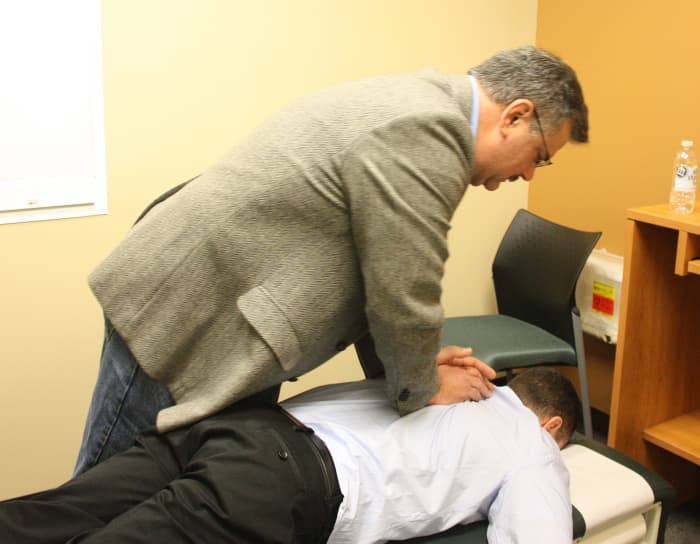 A chiropractor performs a spinal adjustment on his patient.
