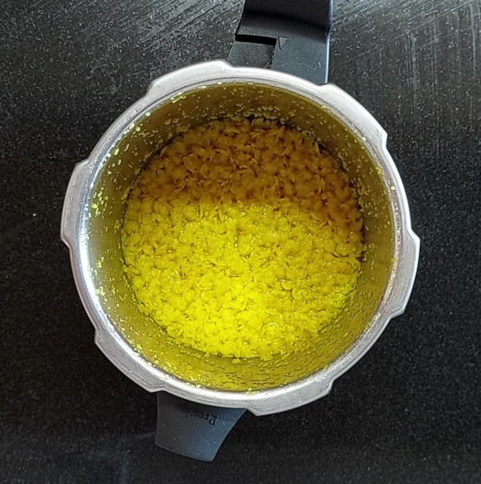 Wash and transfer 1/2 cup of toor dal to a cooker, add 1 cup of water, take 3 whistles, switch off the flame and let the pressure subside naturally.