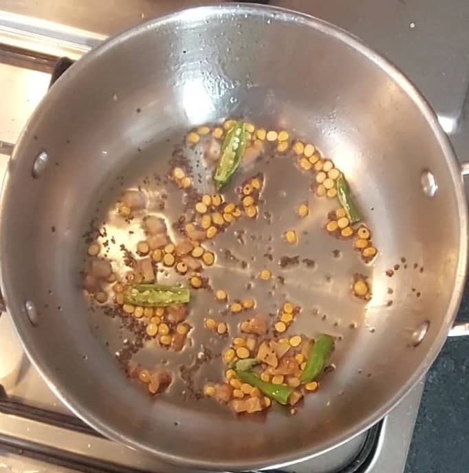In a pan, heat 2 teaspoons oil and splutter 1/2 teaspoon mustard seeds. Add 1 teaspoon chana dal and saute for a few seconds. Add 2-3 chopped green chilies and chopped ginger. Saute well till lentils turn golden brown.