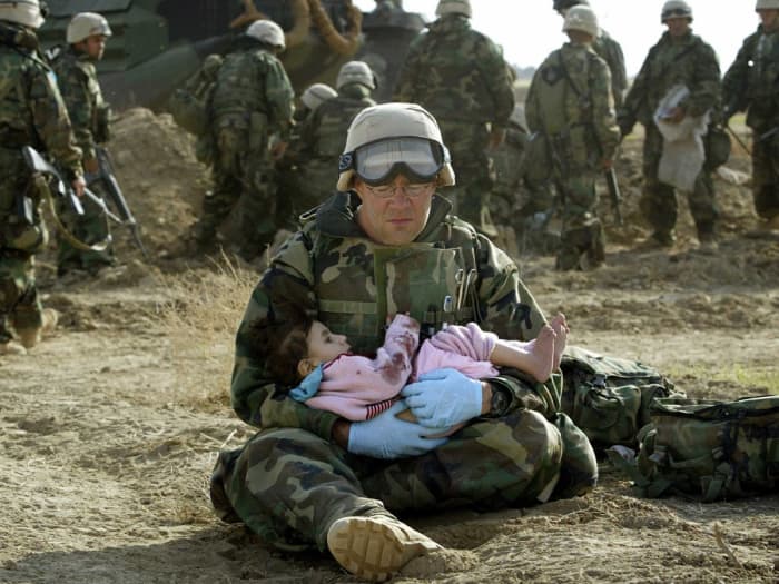 U.S. Navy Hospital Corpsman HM1 Richard Barnett, assigned to the 1st Marine Division, holds an Iraqi child in central Iraq