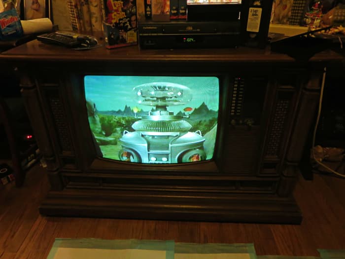 The Robot striking a pose on the Curtis Color Console Model H2508ME. Two people played him Dick Tufeld as The Robot(voice) and Bob May as The Robot.