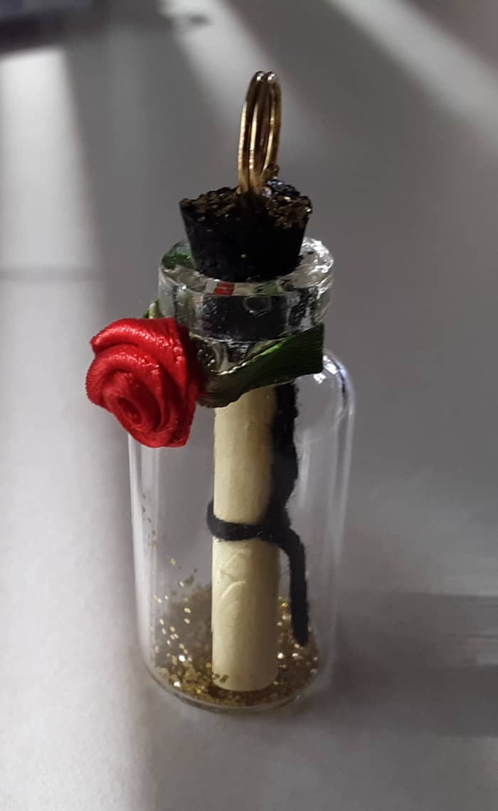 Glue tiny fabric rose to the curve lip of bottle. I painted the rose's leaves lime green before attaching to the bottle, but that is entirely optional.