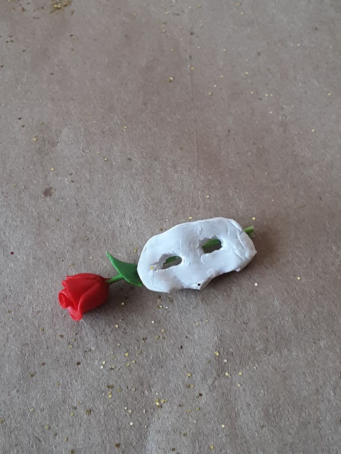 Glue the rose stem to the back of mask. Glue strait so that the mask and rose will easily slip into bottle.