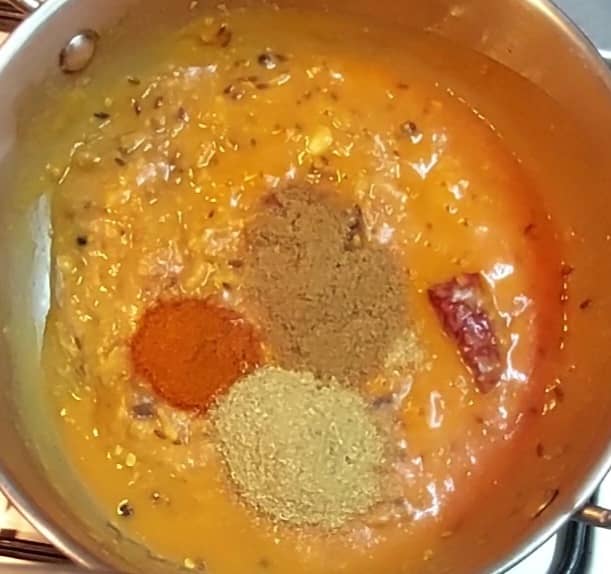 After 2 minutes, add 1/2 teaspoon red chili powder, 1 teaspoon coriander powder and 1 teaspoon cumin powder. Mix and combine well.