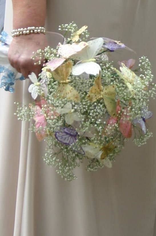 A simple butterfly bouquet made of Baby's Breath and butterflies gives a light touch to the bridal attire