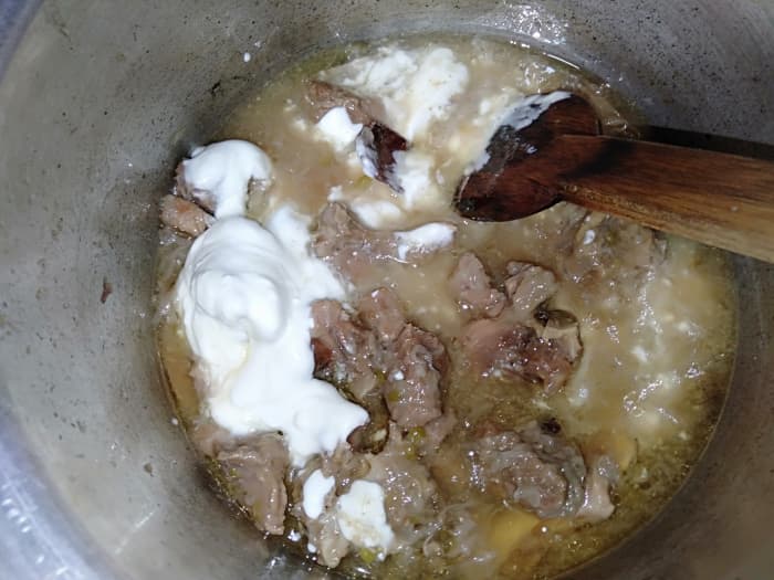 Open the pressure cooker and check the mutton. Once it is tender, add whisked yogurt. Keep the flame low.