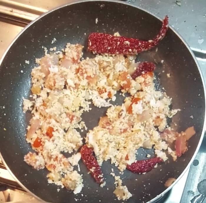 Add 1 chopped tomato and fry till tomato shrinks. Add 1/2 cup grated coconut and 1/2 teaspoon tamarind. Mix well and switch off the flame. Allow the mixture to cool down.