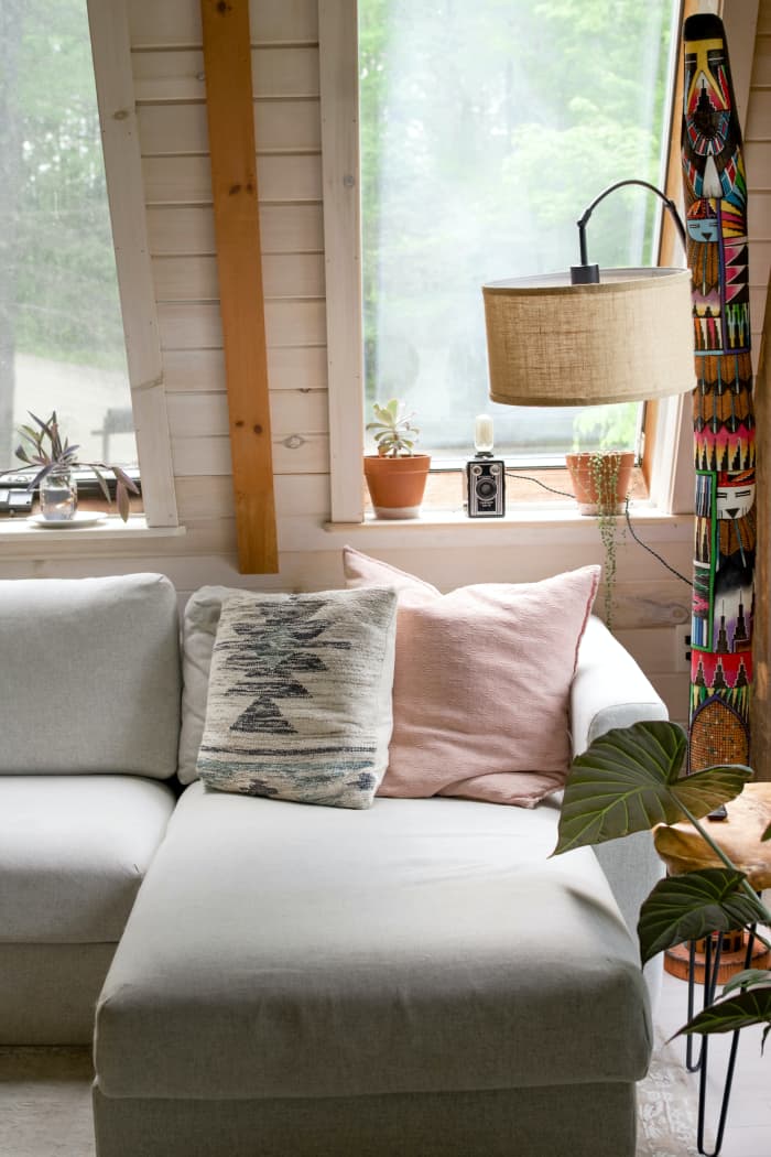 A Libra living room plays with mismatched patterns. There is a hint of pink. It looks cozy like you could sit down and drink a hot cup of tea.
