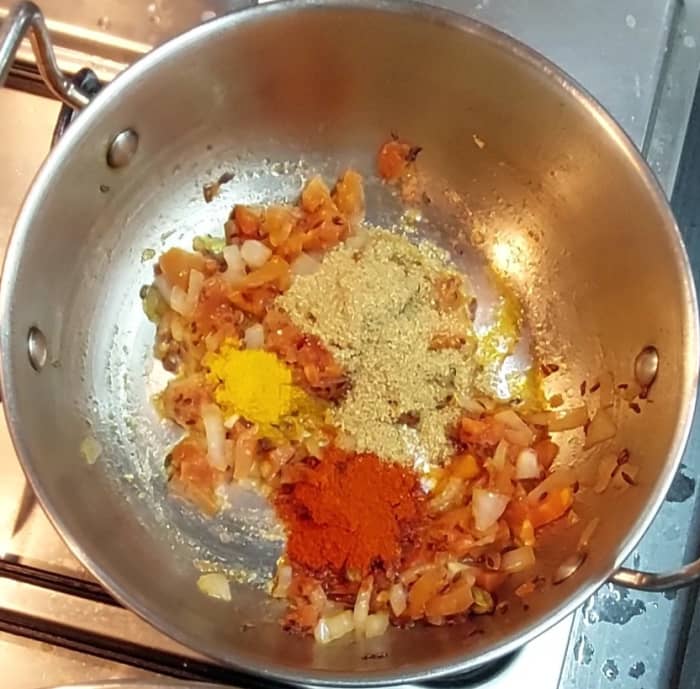 After tomatoes are cooked, open lid and add 1/4 teaspoon turmeric powder, 1 teaspoon red chili powder and 1 teaspoon coriander powder. Saute and combine well.