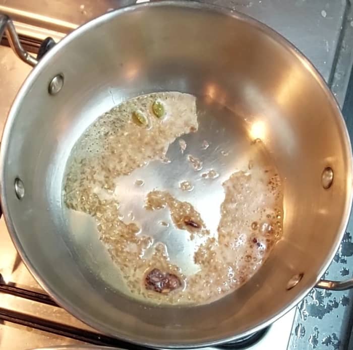In a frying pan, heat 1 tablespoon oil and 1 tablespoon ghee. Splutter 1 teaspoon cumin seeds. Add 2 inch-long cinnamon stick, 2-3 cloves and 2-3 cardamom pods. Saute for a few seconds.