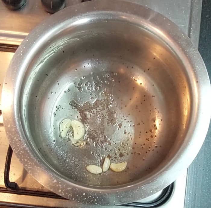 In a vessel, heat 1 tablespoon oil and splutter 1/2 teaspoon mustard seeds. Add 5-6 crushed garlic cloves and 1/4 teaspoon hing. Saute over low flame till garlic turns golden brown.