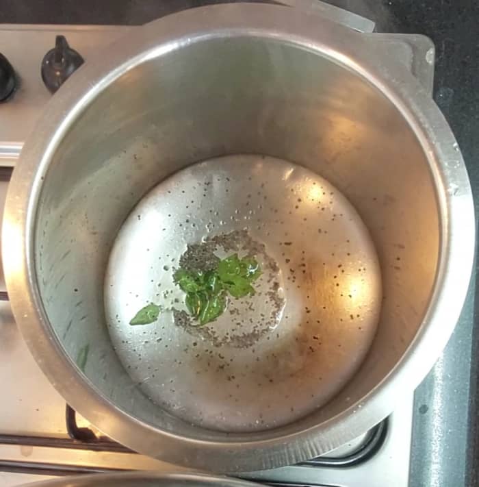 In a vessel or pan, heat 1 teaspoon oil and splutter 1/2 teaspoon mustard seeds. Add a sprig of curry leaves.