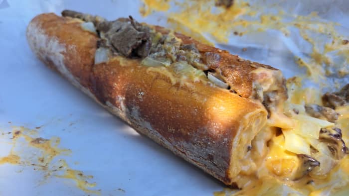 A traditional old-school Philly cheesesteak from Angelo's Pizzeria with steak, Whiz, and fried onions on a seeded roll.