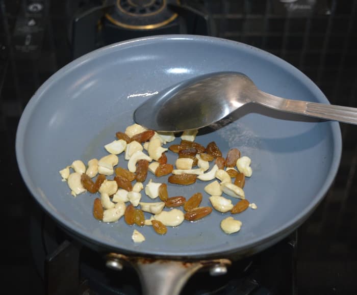 Step three: Heat the ghee in a deep-bottomed pan. Keep it on medium heat. Add cashew nuts. Saute until they turn golden brown. Add raisins and continue to saute for 2-3 seconds. Transfer to a plate.