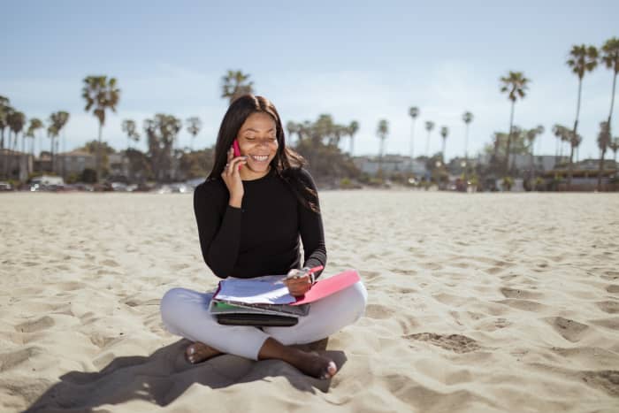 Woman looks busy at work on the beach. Digital economy jobs are on the rise, and these are the jobs that let you work from anywhere.