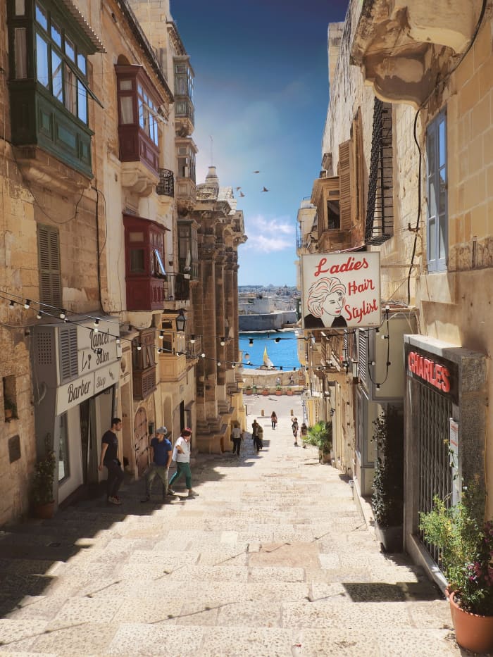Some new signs hanging off old buildings lining ancient streets—that's the living history of Malta all in one picture!