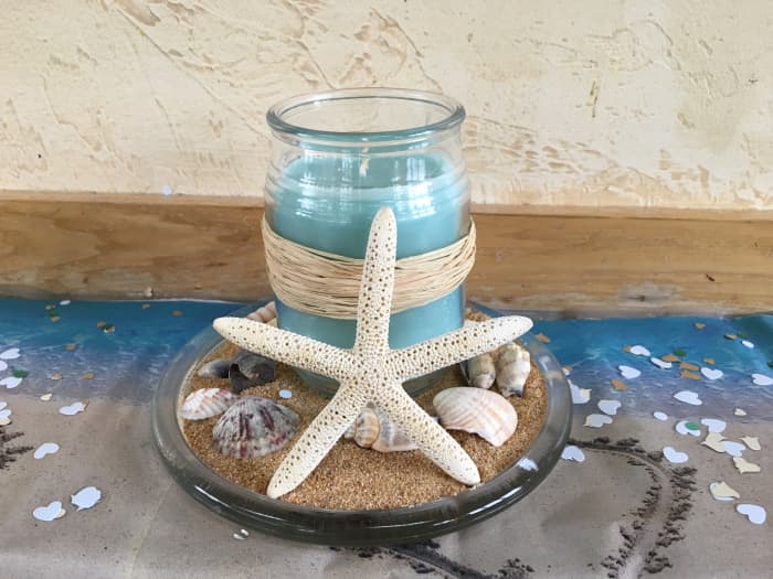 Wrap Raffia ribbon around a candle, place it on a glass dish filled with sand, place shells in the sand and a star fish in front of the candle! Bridal theme table scatter adds a nice, sparkly touch.