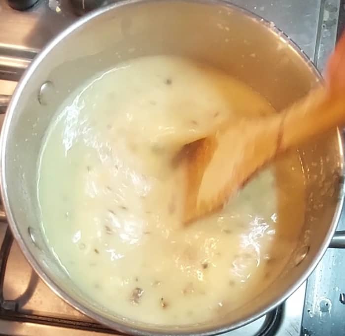 When the water is boiling, turn the flame to medium low; add raosted rava gradually. Stir quickly to avoid forming lumps. Mix well to break the lumps, if any.
