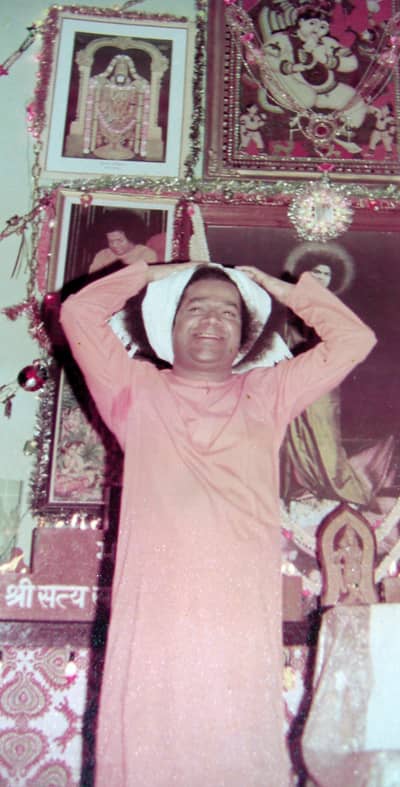 Swami playfully tied a towel to His hair to show how Lord Krishna would do the same when he took the cows out for grazing. In the background there is the picture of Swami on the lotus about which Swami made a special mention in part 2 of this article
