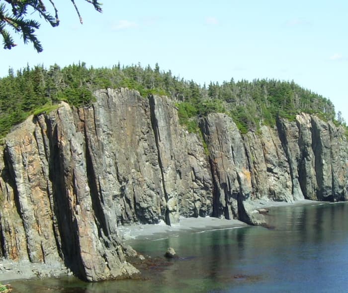 Layers of sedimentary rock, which were once stacked one on another, now stand vertical, side by side, along the coastline of Skerwink Head.