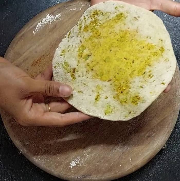 Make a ball, again sprinkle some wheat flour and knead the paratha gently. Dust more flour if required.