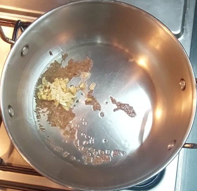 In a frying pan, heat 1 tablespoon oil and splutter 1/2 teaspoon cumin seeds and 1/2 teaspoon carom seeds. Saute for a few seconds. Add 1 teaspoon ginger-garlic paste and saute till raw smell disappears.