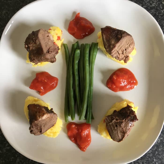 Fried pigeon breast portions are served on quenelled mustard and chilli mash with dwarf beans and spicy tomato sauce.