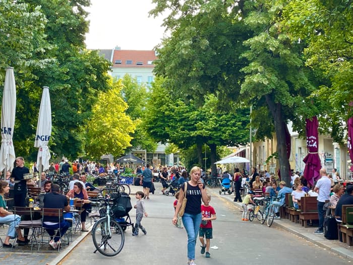 People come together at Lausitzer Platz for a pleasant time in the shade of green lush trees.
