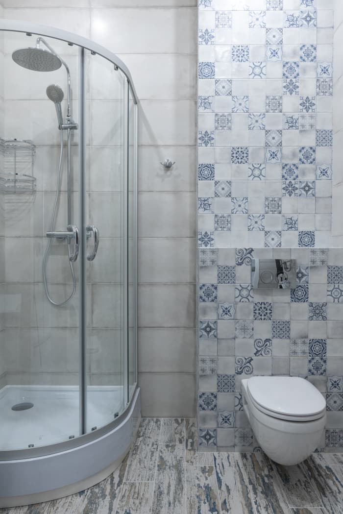 A bathroom that's mostly streamlined in neutral colors with a playful wall of mismatched blue tiles is on point for this sign.