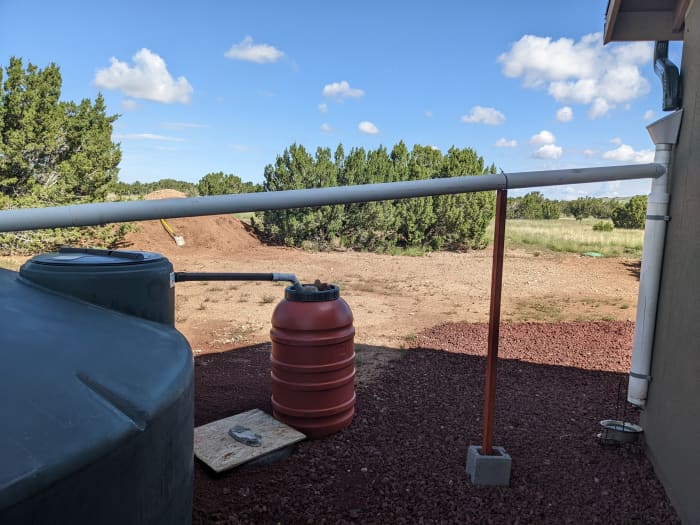 Leaf screens and first flush diverters (vertical PVC on the right side of the picture, against the house) are required parts of a rainwater harvesting system in Coconino County. 