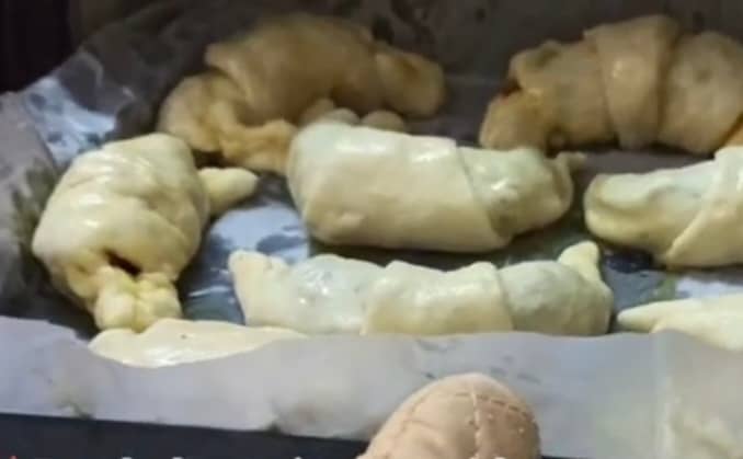Place the croissants on an oven tray and brush with whisked egg. Place the tray in a preheated oven.