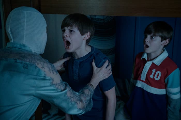 Mother (Naomi Watts) attempts to get Elias (Cameron Crovetti) to get him to say that she is his mother as Lucas (Nicholas Crovetti) watches in, "Goodnight Mommy."