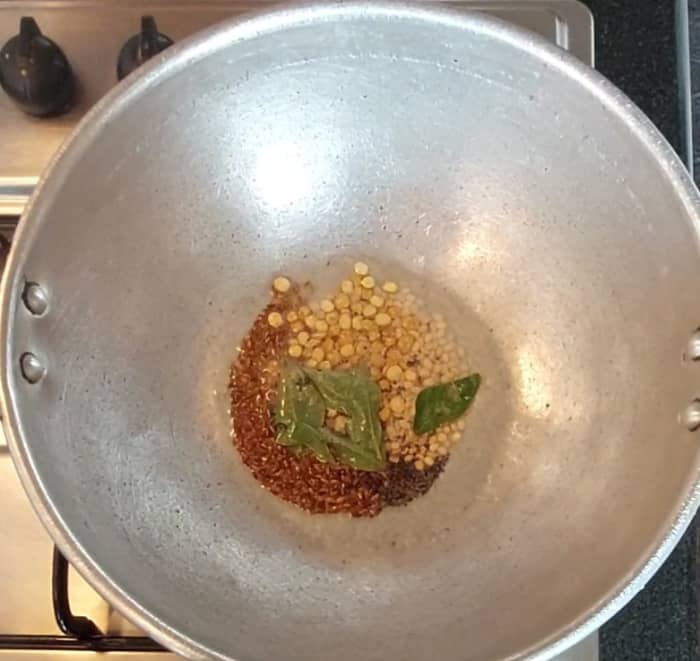In a pan, heat 2 teaspoons oil and splutter 1/2 teaspoon mustard seeds and 1 teaspoon cumin seeds. Add 1 teaspoon urad dal, 1 teaspoon chana dal, a sprig of curry leaves and 1/4 teaspoon hing.