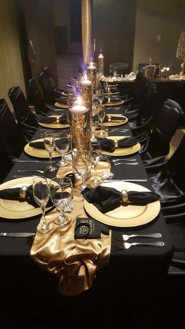 Black and gold - elegant satin napkins and lines floating candles and gold chargers, napkin rings, tulle, and gold runners formal place setting banquet table scape inspired