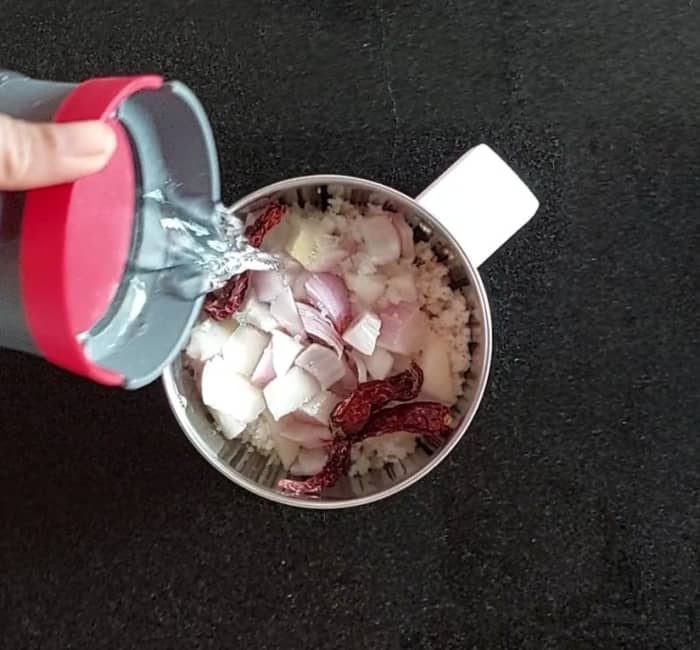 In a mixer jar, add 1/2 cup fresh grated coconut, 1 medium chopped onion, 2-3 red chilies and salt to taste. Add 1/2 cup of water.