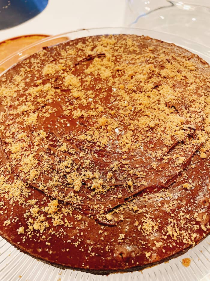 Spread the chocolate ganache of your choice on top of the cheesecake once it's ready. Sprinkle with cookie crumbs or crushed graham crackers.