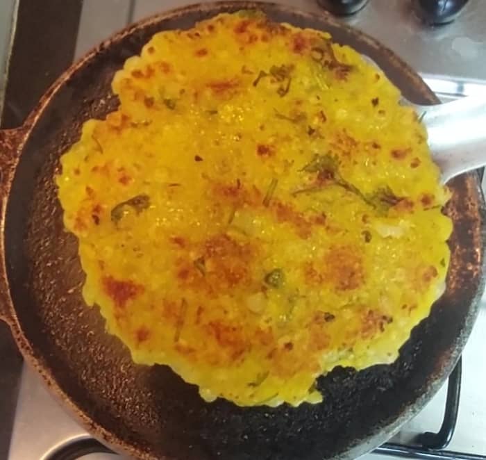 Flip and cook roti on both sides. Drizzle more ghee if required. Cook till brown spots appear. Once done transfer to a plate. Repeat the same procedure with the rest of the roti mixture.