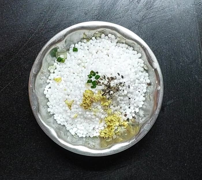 Add the sago to the mashed potatoes. Add 1 teaspoon grated ginger, 1-2 chopped green chilies, and 1 teaspoon crushed black peppercorns.
