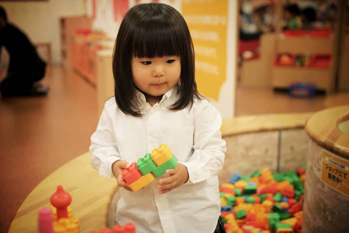 A young preschooler plays with building blocks in a preschool classroom.