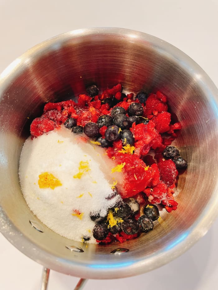 In a small-sized pan, combine the frozen raspberries, blueberries, sugar, lemon zest, and lemon juice.