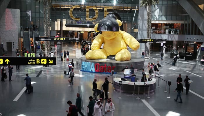 The hallmark of Doha Airport is a giant yellow teddy bear sitting under a black lamp in the departure hall. This is the famous Lamp Bear installation by the Swiss artist Urs Fischer.