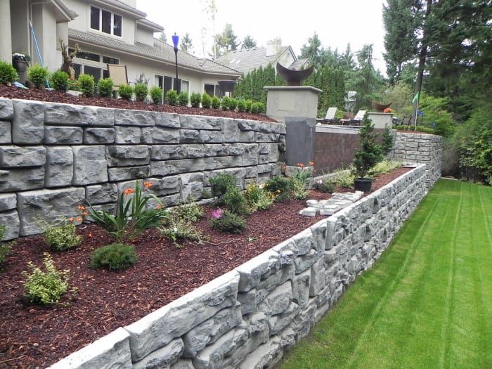 Two-tiered retaining wall in the backyard. Planting flowers and small brushes can soften the look of the stones.