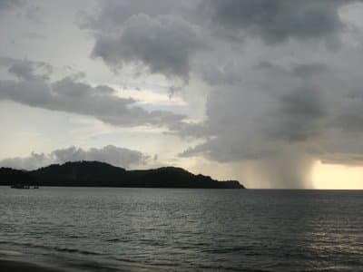 Partly cloudy with scattered rain showers in the afternoon is common during the wet season. A view westward from Playa Panama into Bahia Culebra.