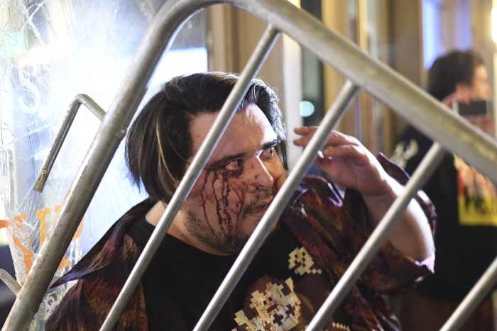 A bystander who said he was attacked by protesters looks for cover amid a UC Berkeley rally against a scheduled speech by Breitbart News editor Milo Yiannopoulos.